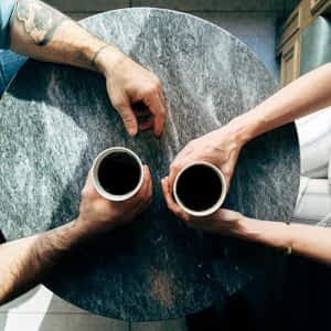 two sets of hands holding coffee cups are seen from above