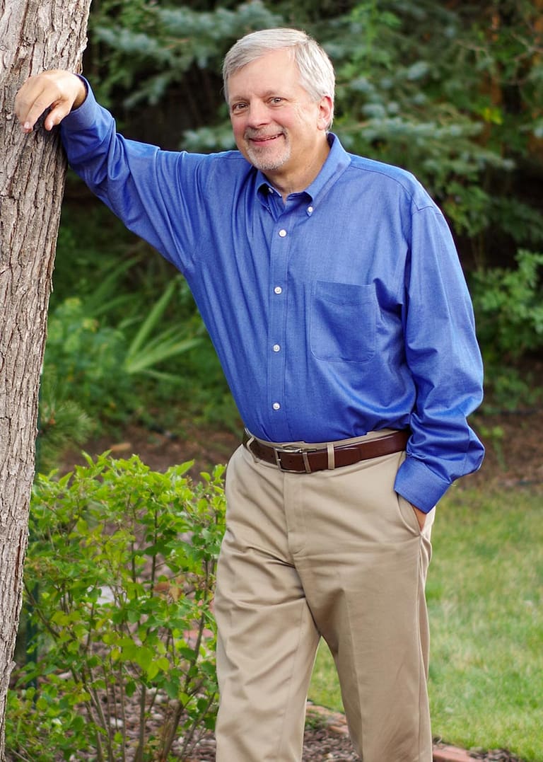 Mark Dorn stands outside against a tree smiling